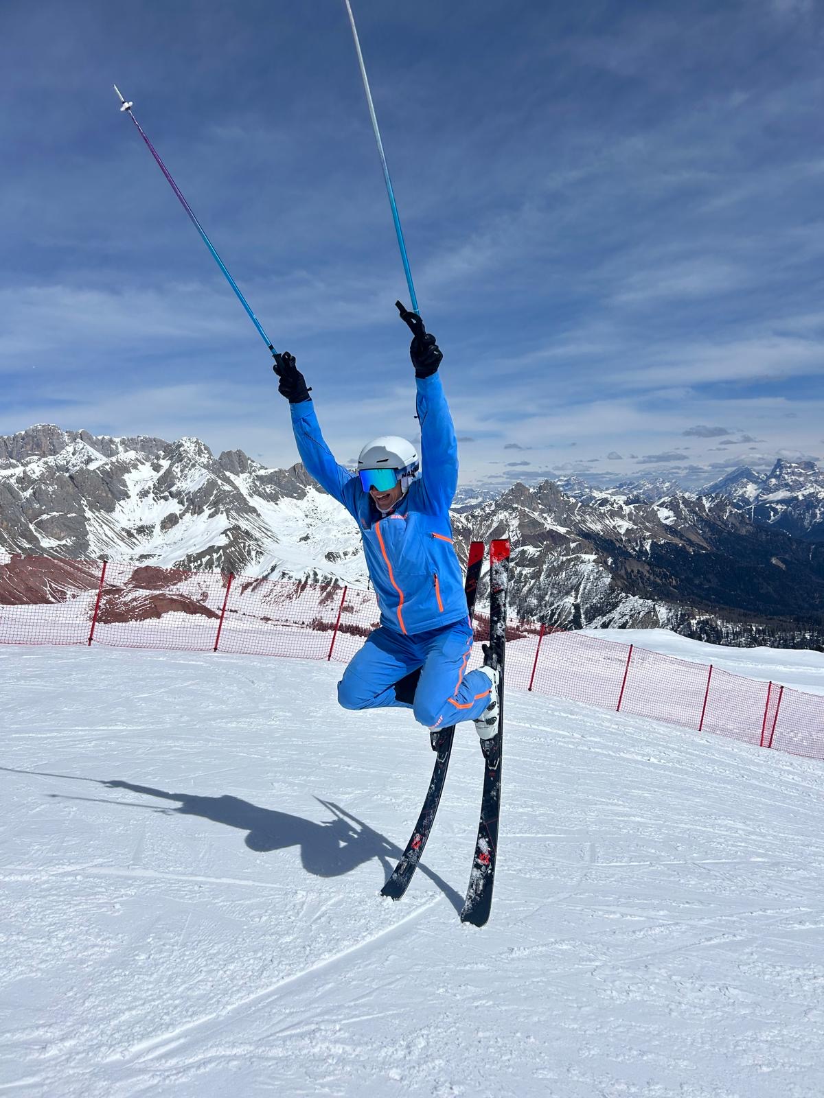 Skifahrer mit in den Schnee-gesteckten Skiern hebt die Hände hoch